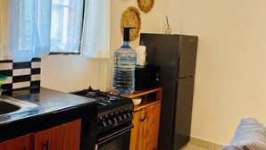 A compact kitchen with a stove, oven, refrigerator, and a water dispenser. - Peaceful home at the heart of Kilifi town, with close proximity to the beach (Kilifi)