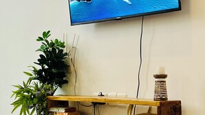 A flat-screen TV mounted on a wall above a wooden console table with books and decorative items. - Peaceful home at the heart of Kilifi town, with close proximity to the beach (Kilifi)