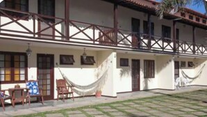 Un edificio a due piani con un balcone, un'amaca e un piccolo patio.