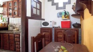 Un'area pranzo con tavolo e sedie in legno, un forno a microonde e una scatola rossa sul bancone.