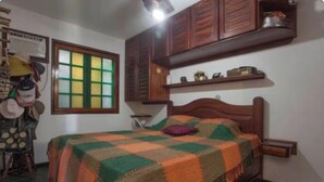 Una camera da letto con un letto di legno, una finestra con vetri verdi e gialli e uno scaffale sopra il letto.