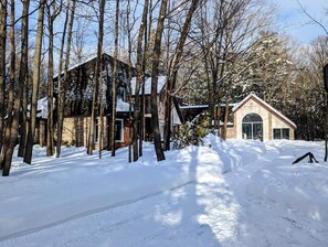 Paisatge nevat amb una cabana de fusta i un edifici petit amb teulat a dos vessants.