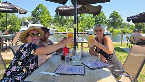 Een buitenterras met tafels, stoelen en parasols.