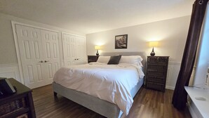 A bedroom with a bed, bedside lamps, a dresser, and a door.