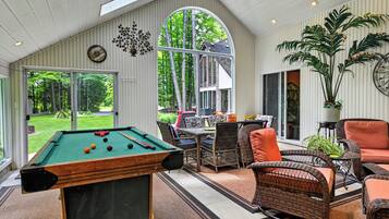 A pool table, wicker furniture, and a view of the outdoors.