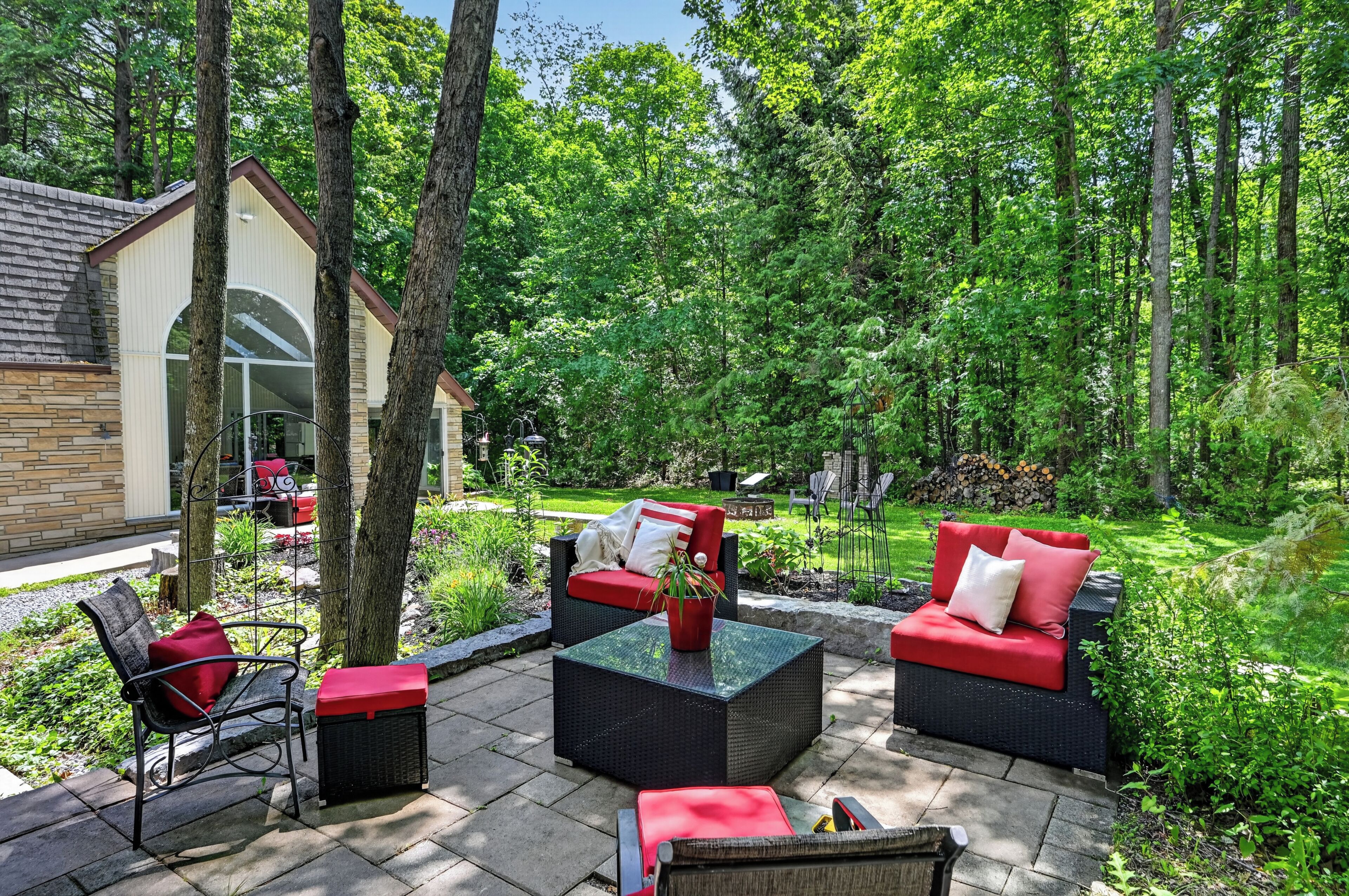 A patio area with outdoor furniture, a small building, and a lush garden.