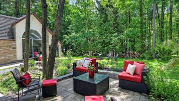 A patio area with outdoor furniture, a small building, and a lush garden.