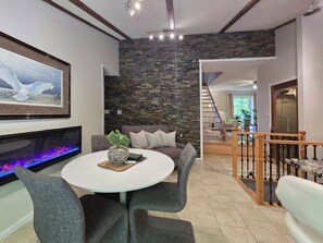 A modern living room with a stone accent wall, a fireplace, a dining area with a round table, and a staircase leading to another level. - Escape. Explore. Unwind.
Easy Access to Rice Lake, Golf, Trails, Snowmobiling. (Asphodel-Norwood)