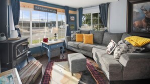 A cozy living room with a sofa, ottoman, and a fireplace. - Fire Pit Backyard, Walk to Town, Close to Glacier, Whitefish,Ski Hill, Northfork (Columbia Falls)