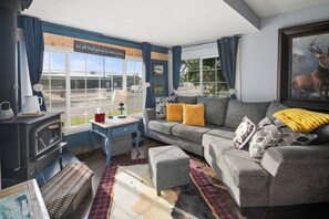 Ein gemütliches Wohnzimmer mit Sofa, Hocker und Kamin.