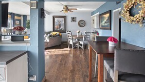 A dining area with a wooden table and chairs, a ceiling fan, and a wall clock. - Fire Pit Backyard, Walk to Town, Close to Glacier, Whitefish,Ski Hill, Northfork (Columbia Falls)