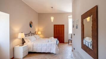 Une chambre à coucher avec un lit, des tables de chevet, un miroir et une porte.