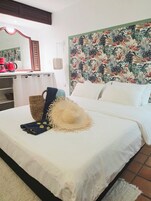 Una cama bien hecha con un sombrero de paja, una cesta tejida y una toalla azul.