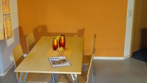 A dining area with a table, chairs, a clock, and a magazine. - Domblick Appartement/Fewo 4-Bettwohnung Nr. 2 by Interhome (Saas-Fee)
