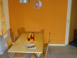 A dining area with a table, chairs, a clock, and a magazine. - Domblick Appartement/Fewo 4-Bettwohnung Nr. 2 by Interhome (Saas-Fee)