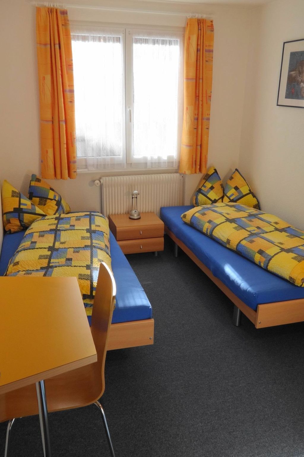 Ein Zimmer mit zwei Betten, einem Schreibtisch und einem Stuhl.