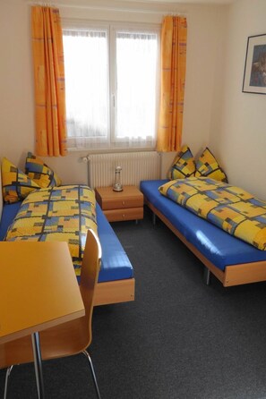 Une chambre avec deux lits, un bureau et une chaise.