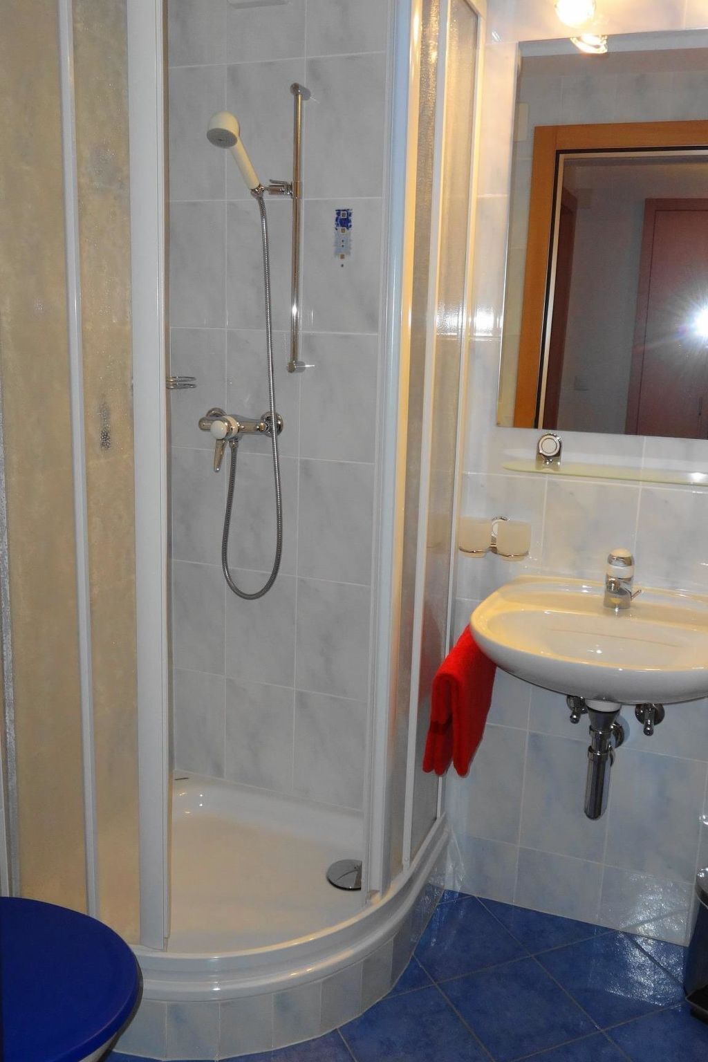 Een badkamer met een douche, een wastafel en een spiegel.