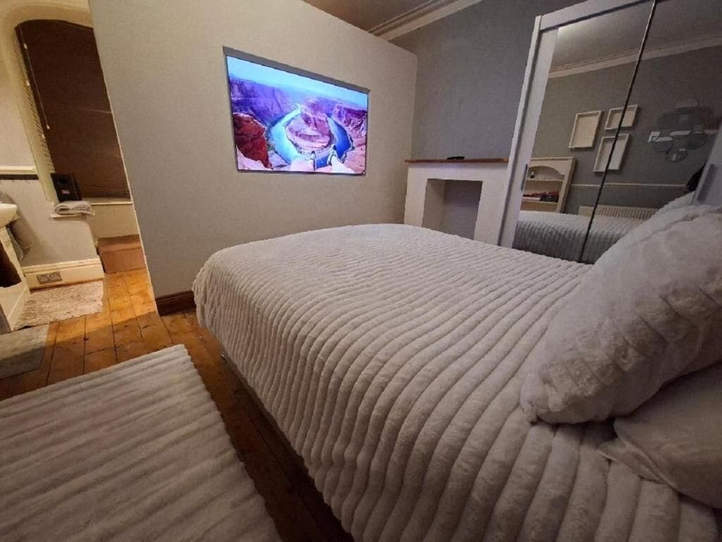 Une chambre à coucher avec un lit, un téléviseur fixé au mur et un miroir.
