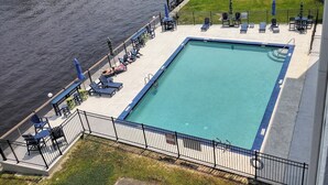 A rectangular swimming pool with a blue edge, surrounded by a black metal fence. - 2-bedroom condo Myrtle Beach with Waterway Views (Myrtle Beach)