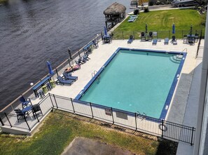 A rectangular swimming pool with a blue edge, surrounded by a black metal fence. - 2-bedroom condo Myrtle Beach with Waterway Views (Myrtle Beach)