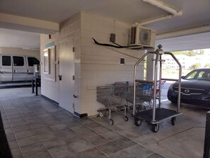 En parkeringskælder med hvide vægge, en ventilationsenhed og en indkøbsvogn.