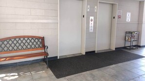 A hallway with a bench, two doors, a fire alarm panel, and a small bookshelf. - 2-bedroom condo Myrtle Beach with Waterway Views (Myrtle Beach)