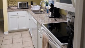 A kitchen with white cabinets, a microwave, a toaster, and a stove. - 2-bedroom condo Myrtle Beach with Waterway Views (Myrtle Beach)