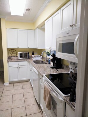 A kitchen with white cabinets, a microwave, a toaster, and a stove. - 2-bedroom condo Myrtle Beach with Waterway Views (Myrtle Beach)