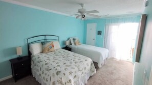 A bedroom with a bed, a nightstand, a ceiling fan, and a door. - 2-bedroom condo Myrtle Beach with Waterway Views (Myrtle Beach)