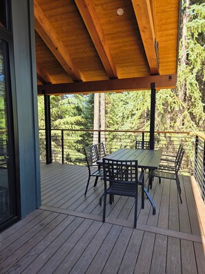 Eine Holzterrasse mit Tisch und Stühlen mit Blick auf ein bewaldetes Gebiet.