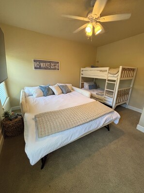 A bedroom with a bed, bunk beds, a ceiling fan, and a 'No Wake Zone' sign.