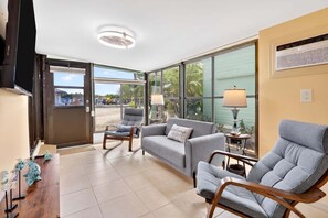 A spacious living area with a sofa, armchairs, a coffee table, and a television. - Key Largo Tiny House, Marina, Beach + Pool Access (Key Largo)