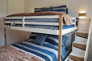 A bunk bed with striped bedding, a bedside table, and a wall-mounted light fixture. - Modern Beach House with Beach Access (Sea View Center)