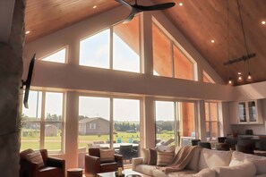 A spacious living area with large windows, a ceiling fan, and a view of the outdoors. - Modern Beach House with Beach Access (Sea View Center)