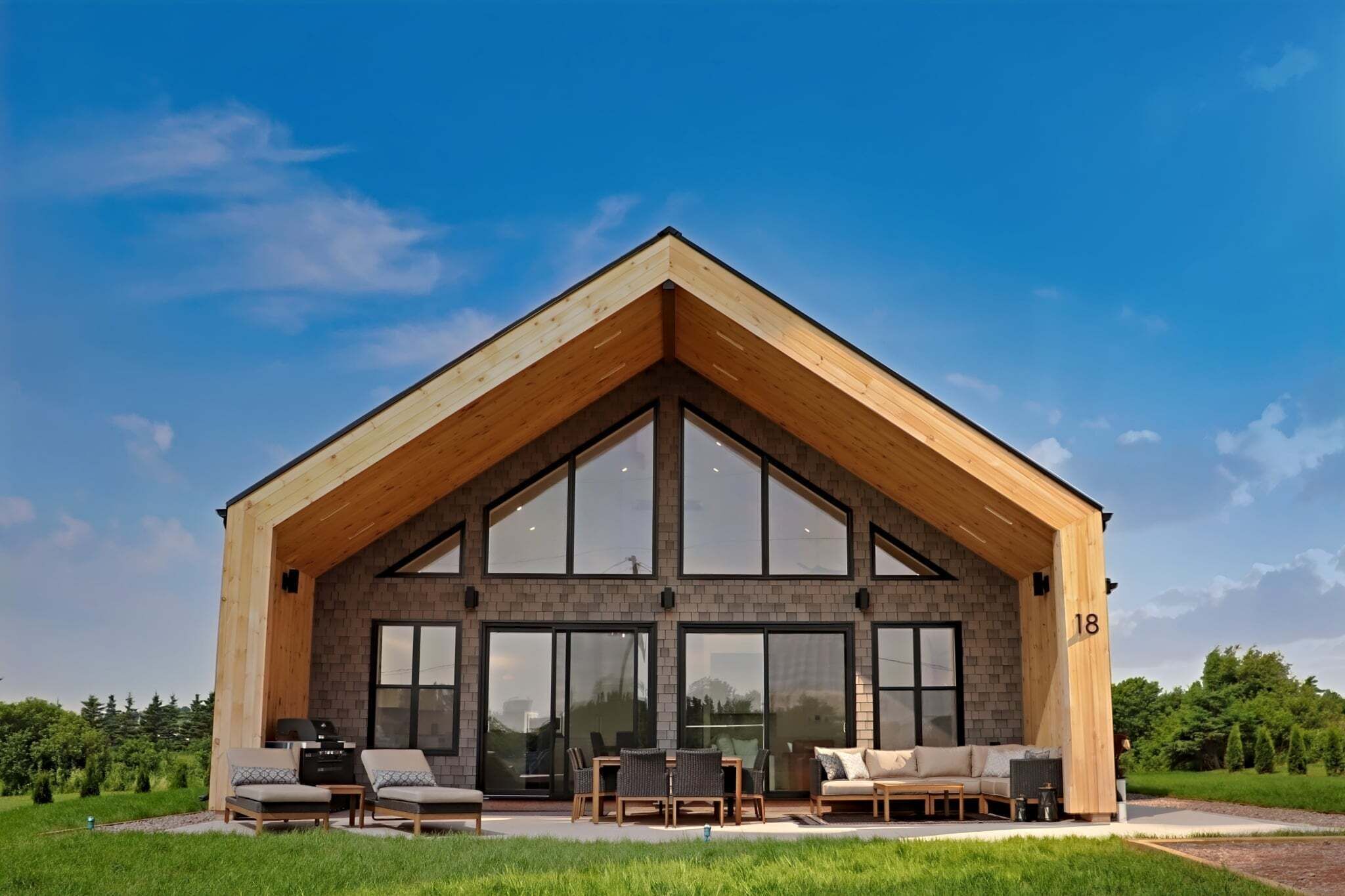 A modern house with a large front porch, large windows, and a number 18 on the side.