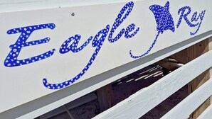 Ein weißes Holzschild mit blauer Schrift, die 'Eagle Ray' beschreibt.