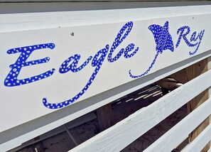 Ein weißes Holzschild mit blauer Schrift, die 'Eagle Ray' beschreibt.