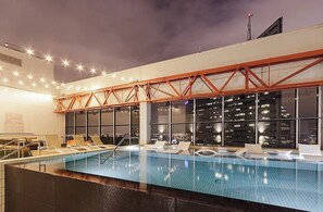 An indoor swimming pool with lounge chairs and a city view. - Luxury Downtown Dallas Penthouse w/ Rooftop Pool, Gym, Free Parking (Dallas)