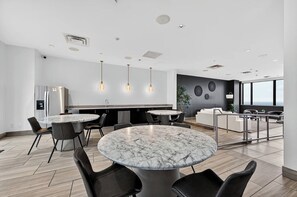 A modern kitchen with a marble island, pendant lights, and a seating area with a view. - Luxury Downtown Dallas Penthouse w/ Rooftop Pool, Gym, Free Parking (Dallas)