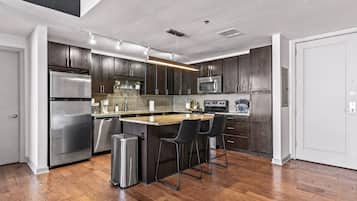 A modern kitchen with dark wood cabinets, stainless steel appliances, and a central island with bar stools.