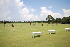 Ein Golfplatz mit weißen Bänken, blauem Himmel und Spielern in der Ferne.