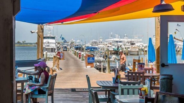 A marina with boats docked, a wooden deck, and outdoor seating areas with tables and chairs. - 2 Golf Carts☀️ On Raven Golf Course | Heated Pool | Hot Tub | Gym | Beach Gear ☀️Sandestin (Miramar Beach)