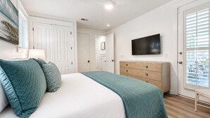 A bedroom with a bed, a TV, a dresser, and a door with blinds. - 2 Golf Carts☀️ On Raven Golf Course | Heated Pool | Hot Tub | Gym | Beach Gear ☀️Sandestin (Miramar Beach)