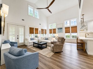 A spacious living room with a high ceiling, a ceiling fan, and large windows with blinds. - 2 Golf Carts☀️ On Raven Golf Course | Heated Pool | Hot Tub | Gym | Beach Gear ☀️Sandestin (Miramar Beach)