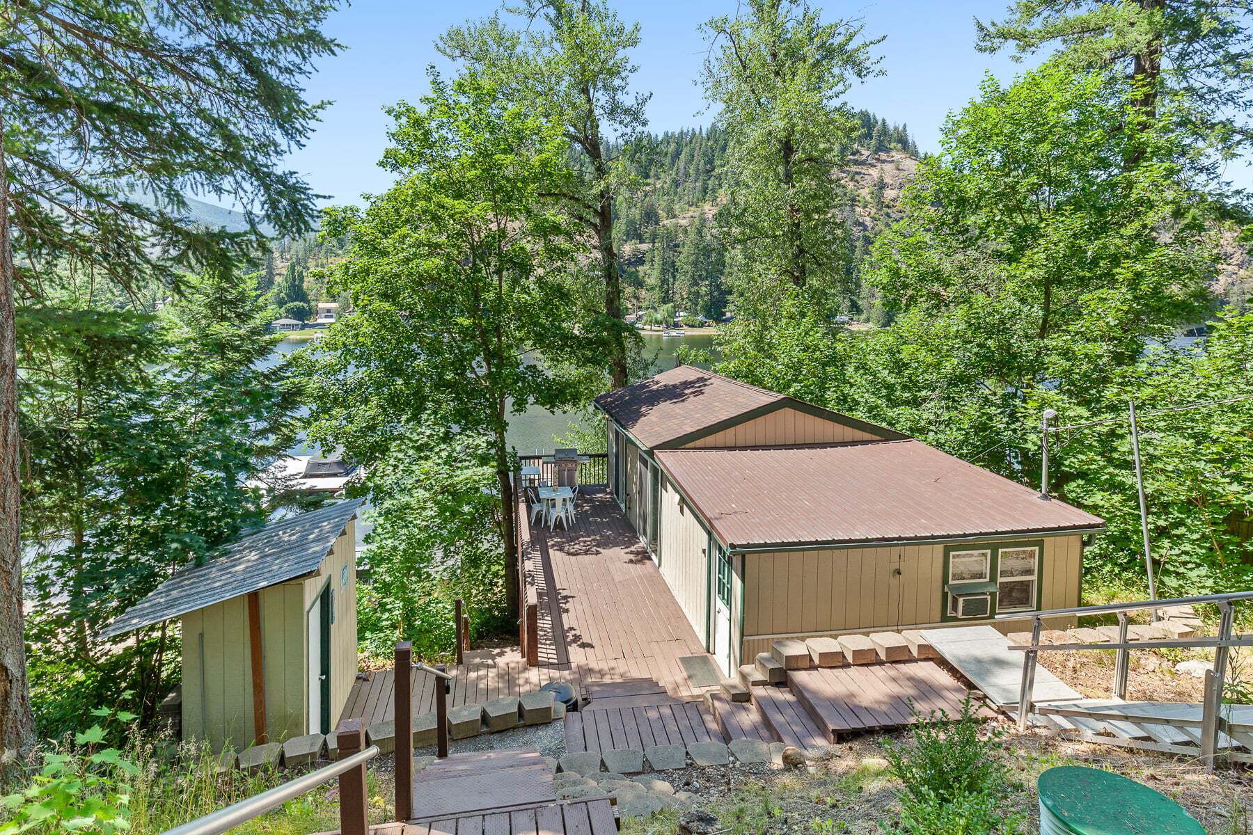 Una cabaña con terraza, rodeada de árboles y vistas al lago.