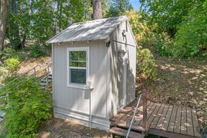 A small, single-story shed with a metal roof, a window, and a door. - Rustic Twin Lakes Cabin | Private Dock, SUPs (Rathdrum)
