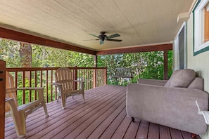 A covered porch with a ceiling fan, wooden deck, and a sofa. - Rustic Twin Lakes Cabin | Private Dock, SUPs (Rathdrum)
