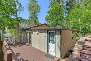 A wooden deck with outdoor seating and a small building with a door and windows.