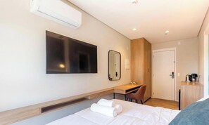 A hotel room with a bed, a desk, a chair, a flat-screen TV, a mirror, and a door. - Comfort in Condo. w/ gym in SP Hmj0411 (São Paulo)